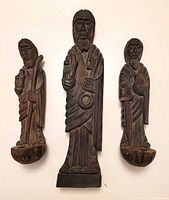 front view of three carved wood saint figures showing design and candle bowls