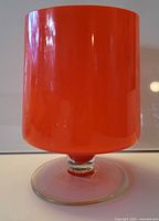 Front view of orange cased glass vase on clear foot