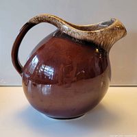 Front view of spherical brown drip-glaze Hull water pitcher showing loop handle and glossy finish