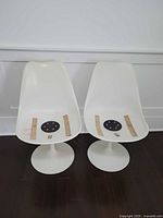 Front view of two white Knoll Tulip chairs without cushions