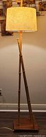 Full view of illuminated bamboo floor lamp with fiberglass shade