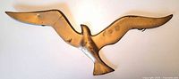 Front view of gold-tone metal seagull wall sculpture