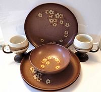 Front view of all six items: three Denby plates, one Denby bowl, two Otagiri pedestal mugs