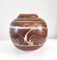 Full view of bulbous brown vase with cream swirl decoration