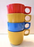 Stack of four melamine cups red, yellow, blue, yellow
