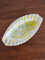 Top view of white ceramic oval splatter ashtray with green and yellow pattern
