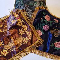 Three satin souvenir pillow shams overlapping showing colors and fringe