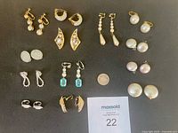 Overview of assorted earrings laid out on black background with coin for scale