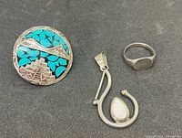Front view of three sterling silver pieces: turquoise inlay round pendant, opal accent pendant, plain band ring