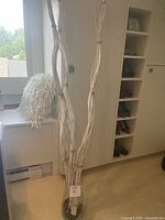 Full view of tall white twig arrangement in glass vase