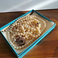 Two faux pearl beaded necklaces displayed in a blue jewellery box