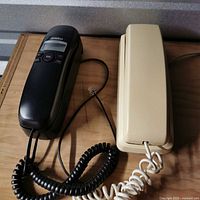 Black Uniden phone beside beige phone on table