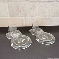 Two clear plastic teacup-saucer holders on black surface