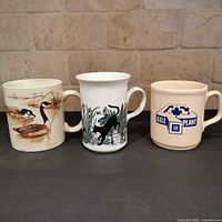 Front view of three ceramic mugs showing designs