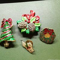 All four enamel holiday brooches displayed