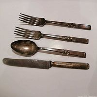 Full view of four silverplate utensils: two forks, spoon, knife