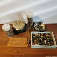 Full lot view: soldering paste tin, two vials, sharpening stone pouch, metal dish, metal box of screws
