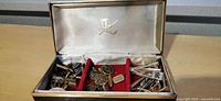 open case showing assorted cufflinks and tie clips