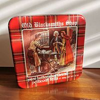 Front of rectangular plaid tin showing illustration and product details