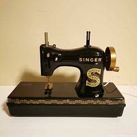 Front view of black Singer toy sewing machine on base