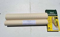 Two beige wallpaper rolls labeled Arte beside Richard wallpaper installation kit box