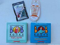 Overall view of both Bob Books sets, EZ Laces pack, and practice shoe