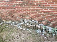 Stack of assorted concrete pavers against brick wall