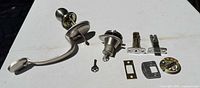Full set laid out: lever handle, lock cylinder, latches, strike plates, key, screws