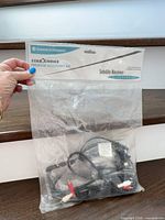 Full view of torn plastic bag showing accessory kit and cables