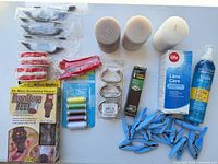 All items laid out showing candles, thread spools, clothespins, handles, contact lens solution, mousse, Furniture Feet box, Philips item, tape rolls, light bulb pack