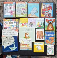 All sixteen children’s board and picture books laid out in four rows on table