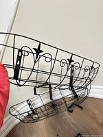 Two black metal window boxes with scroll design and brackets