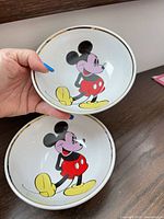 Two white stoneware bowls with Mickey Mouse graphic and gold rim
