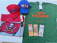 Group shot showing T-shirt, two Bills caps, folded Buccaneers banner, three tickets