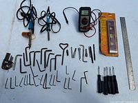 All items laid out: multimeter, soldering irons, butane torch, rulers, levels, hex keys, screwdrivers, drill bits