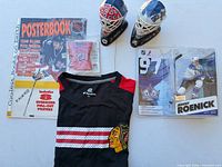 All items grouped: T-shirt, posterbook, two mini helmets, action figure, mini jersey