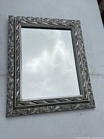 Front view of rectangular mirror showing ornate silver frame and reflective glass
