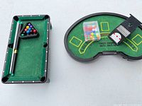 Mini pool table with cues, balls in rack; blackjack board with card shoe and chip box