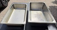 Overhead view of solid and perforated full-size stainless steam table pans