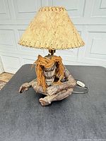 Front view of carved wood tiki lamp with natural fiber shade and cord