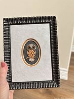 Full view of framed owl brooch art piece in hand