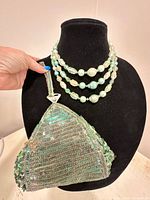 Necklace draped on bust with evening bag hanging alongside showing overall view