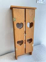 Front view of pine wall cabinet showing doors with heart cutouts and brass hinges