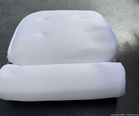 Front view of white mesh foam bath pillow showing rectangular backrest and cylindrical neck roll