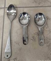 Three stainless steel spoons laid side by side