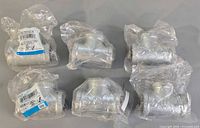 Six individually bagged galvanized T-couplings on surface
