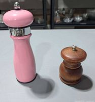 Pink gloss tall mill and small natural wood mill side by side on tabletop