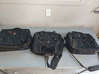 Three black SwissGear laptop bags laid flat showing overall styles and size comparison