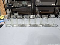 All eight clear glass mason jars lined in a row