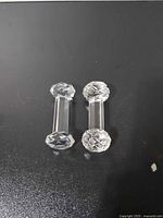 Two clear cut glass knife rests side by side on dark background